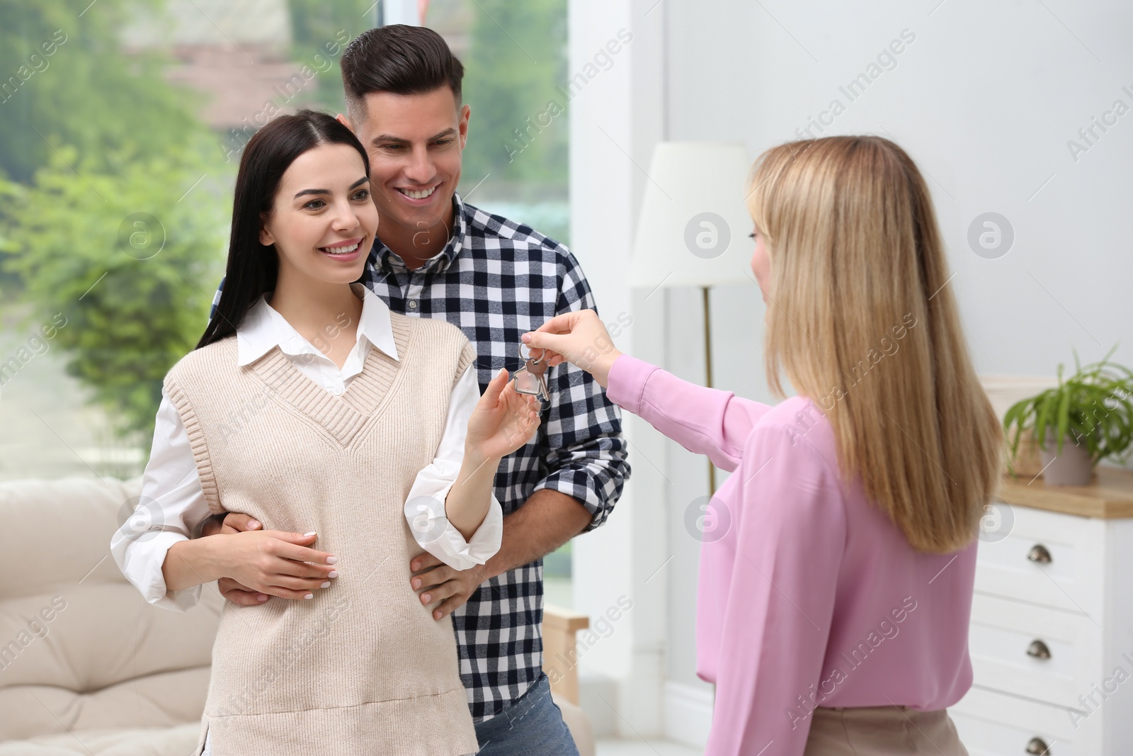 Photo of Real estate agent giving house key to couple at home