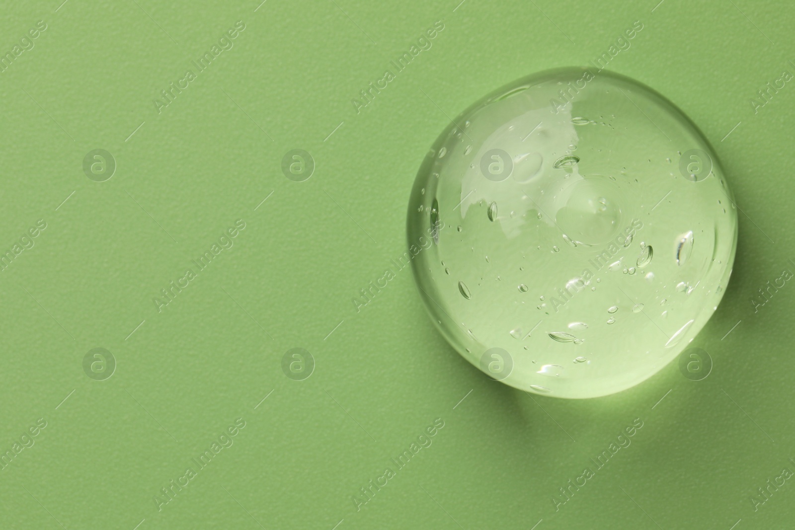 Photo of Sample of clear cosmetic gel on light green background, top view. Space for text
