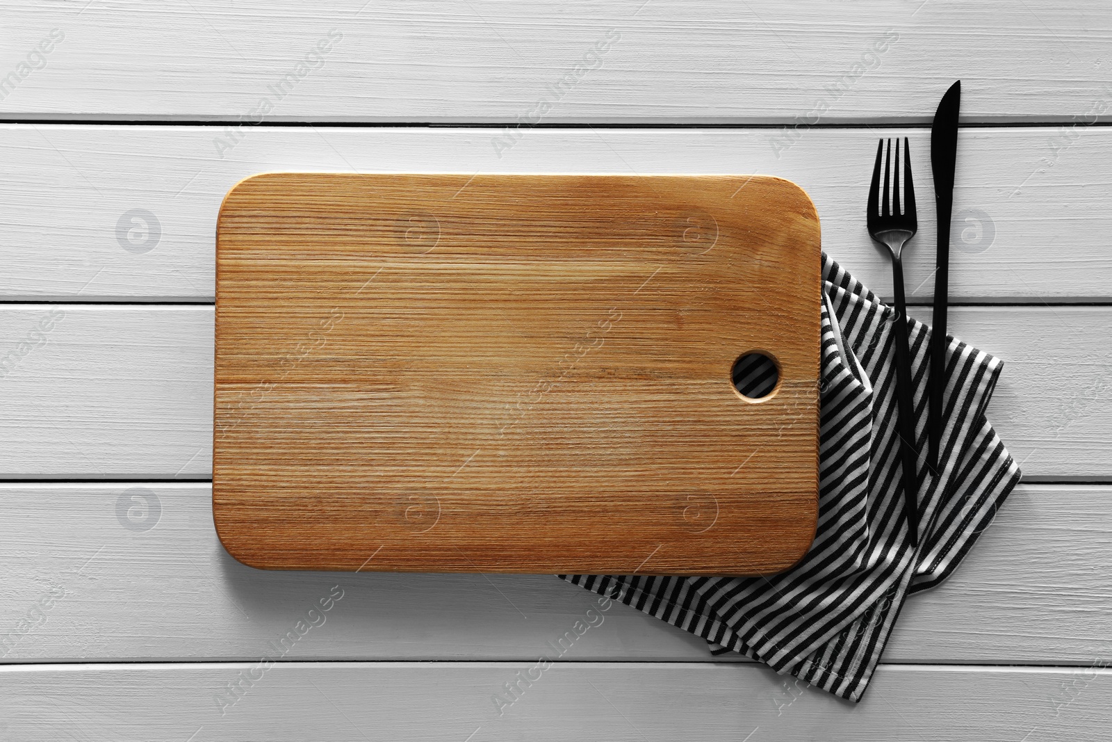 Photo of Empty board with cutlery and napkin on white wooden table, flat lay