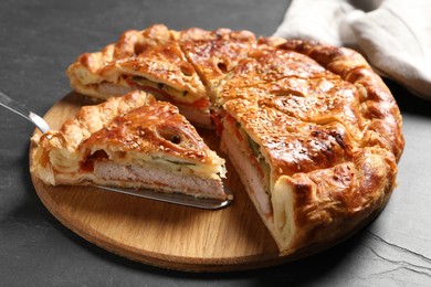 Photo of Cut delicious homemade pie and server on black table, closeup