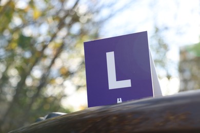 L-plate on car outdoors, space for text. Driving school
