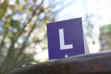 Photo of L-plate on car outdoors, space for text. Driving school