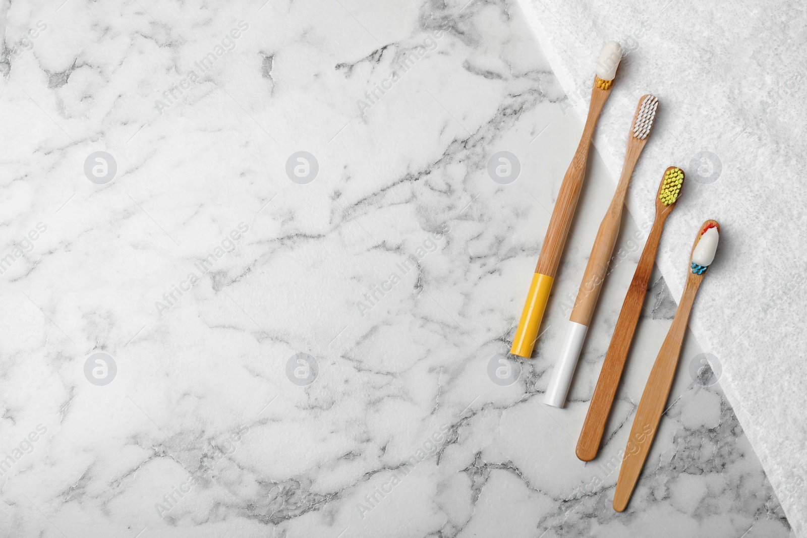 Photo of Flat lay composition with bamboo toothbrushes, towel and space for text on marble background