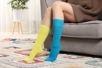 Photo of Woman in different stylish socks in armchair indoors, closeup