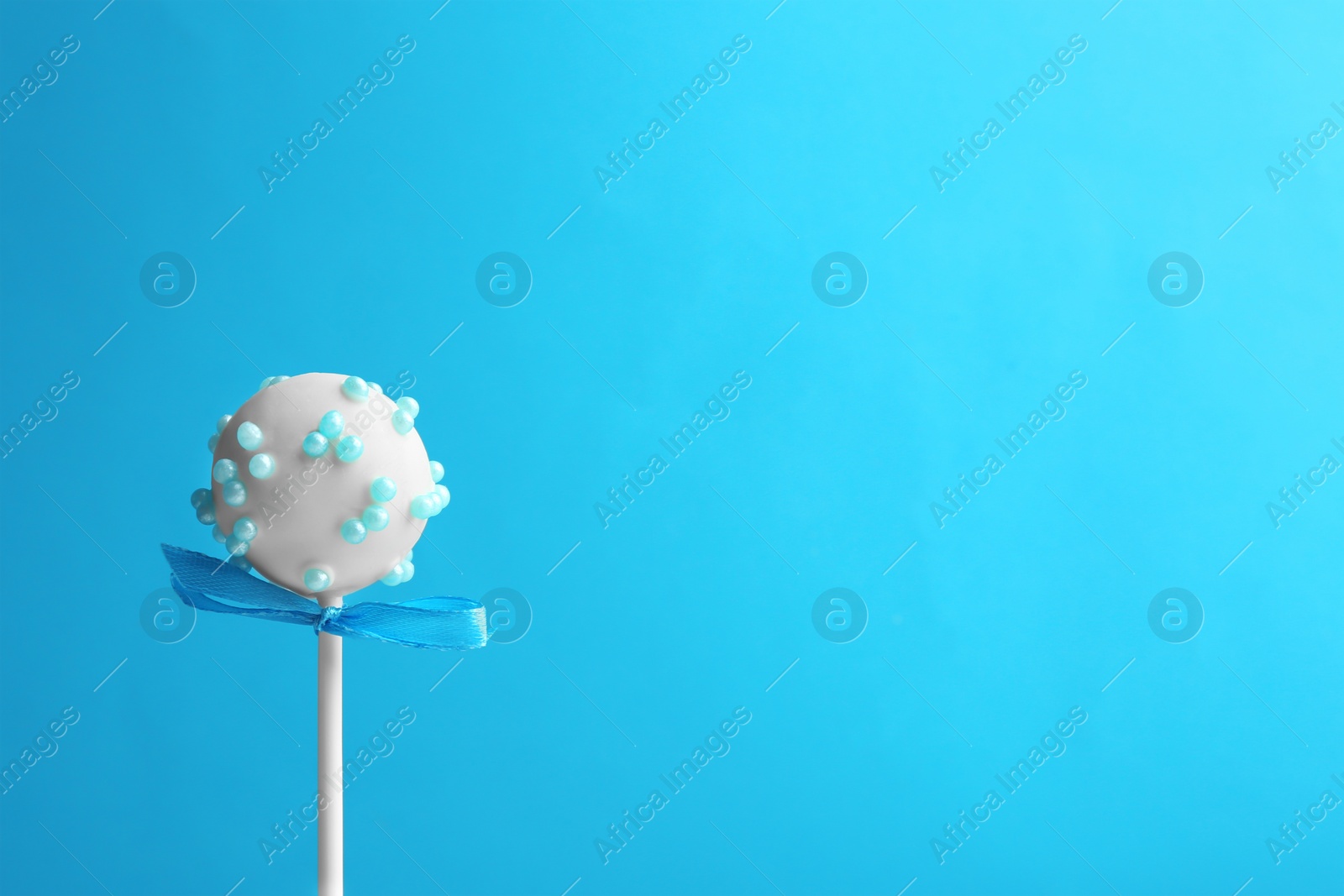 Photo of Tasty cake pop with bow on light blue background