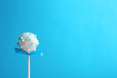 Photo of Tasty cake pop with bow on light blue background