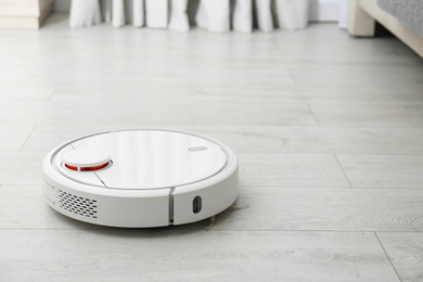 Hoovering floor with modern robotic vacuum cleaner indoors. Space for text