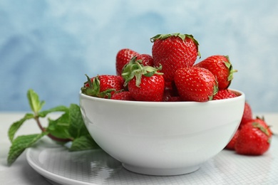 Photo of Bowl with ripe red strawberries on table