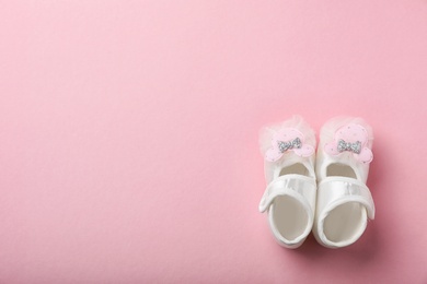 Pair of cute baby sandals on color background, top view