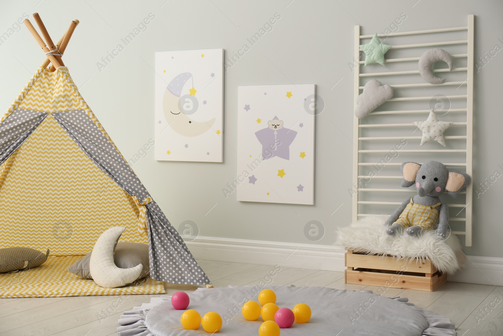 Photo of Stylish child's room interior with adorable paintings and play tent