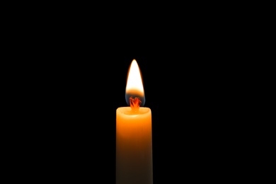 Photo of Wax candle burning on black background