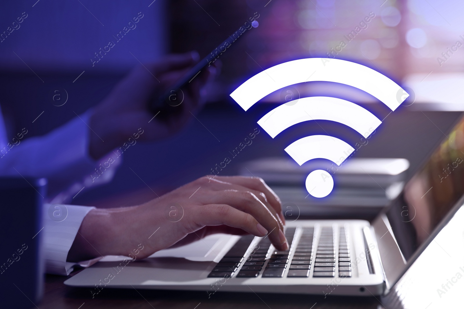 Image of Woman using laptop and smartphone connected to WiFi at table indoors, closeup