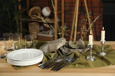 Photo of Clean dishes, stones and plants on wooden table in stylish dining room