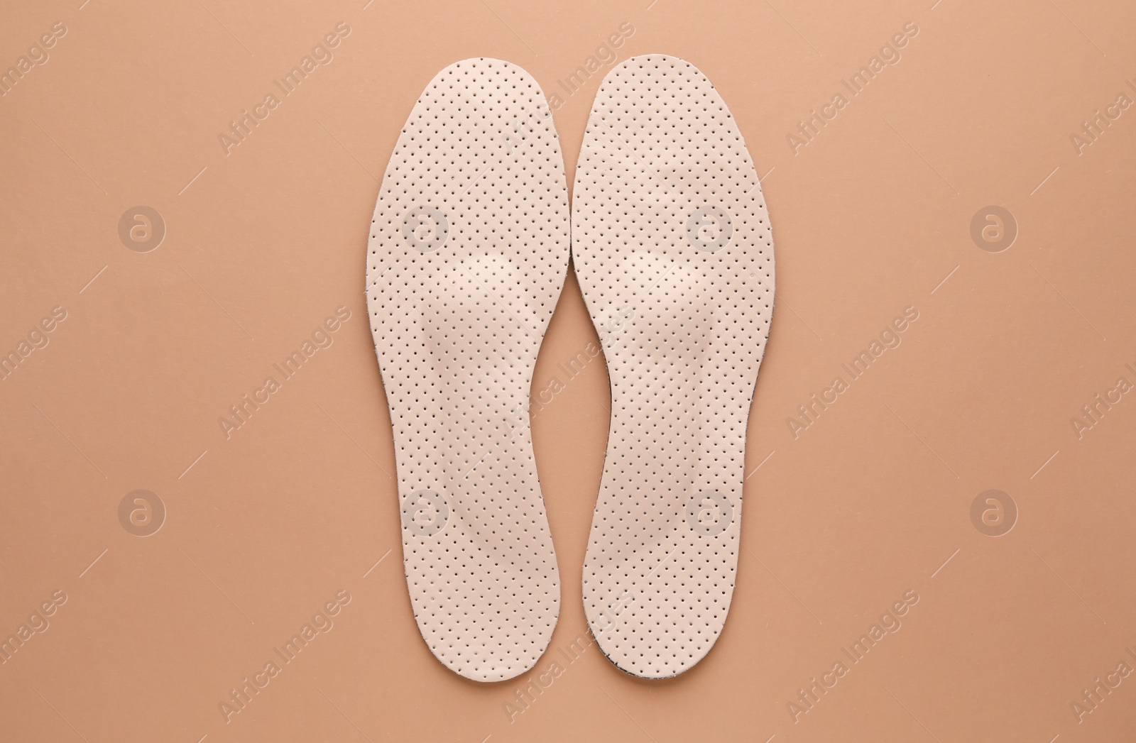 Photo of Orthopedic insoles on pale pink background, flat lay