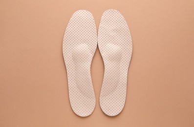 Photo of Orthopedic insoles on pale pink background, flat lay