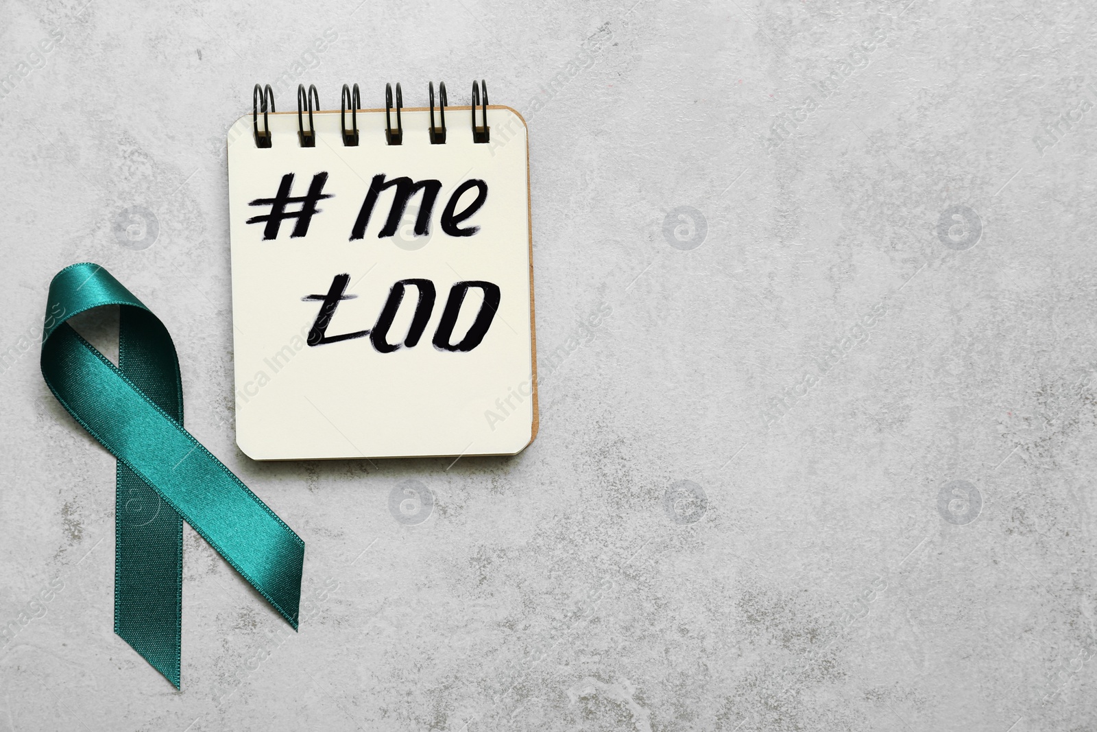 Photo of Teal awareness ribbon and notebook with hashtag METOO on grey background, flat lay. Stop sexual assault