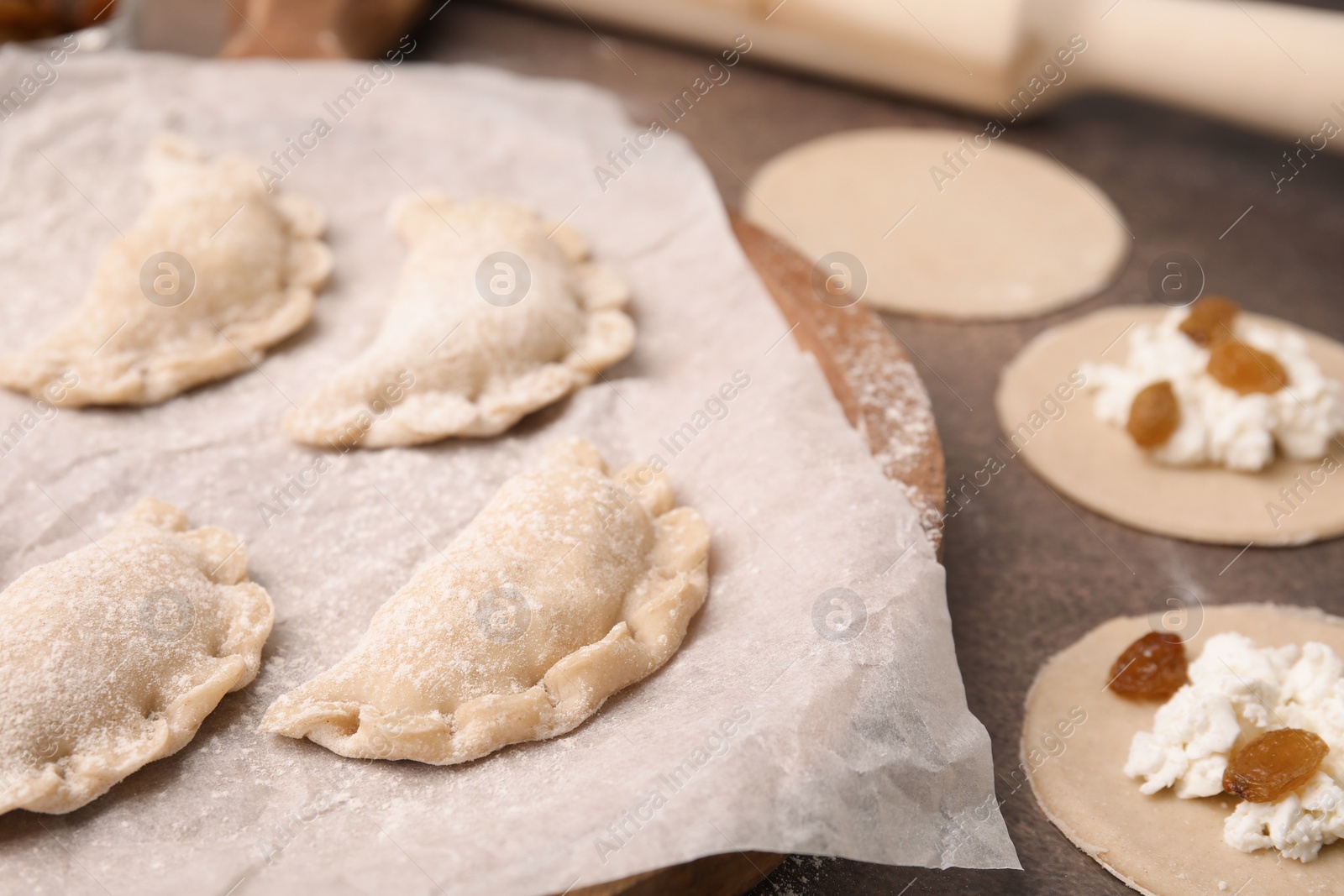 Photo of Process of making dumplings (varenyky) with cottage cheese. Raw dough and ingredients on brown table, closeup