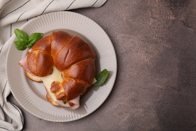 Photo of Tasty crescent roll with ham, cheese and basil on grey table, top view. Space for text