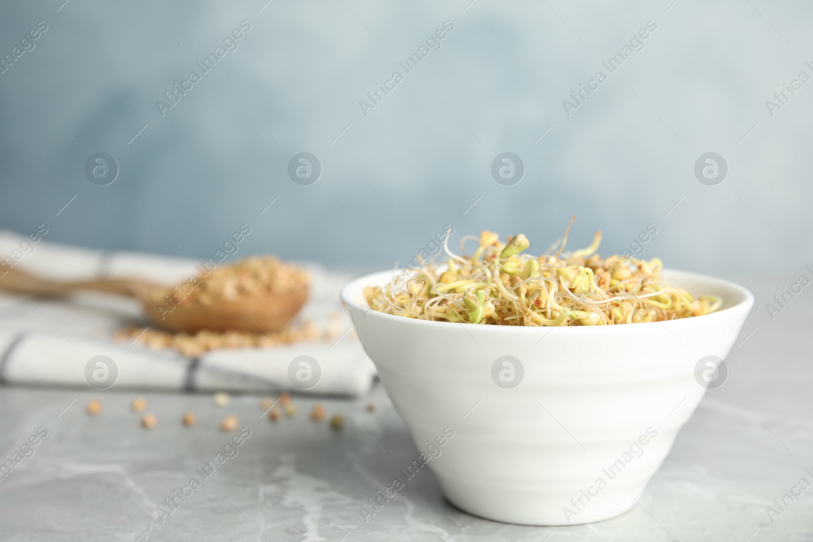 Photo of Bowl with sprouted green buckwheat on light grey table