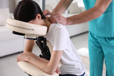 Woman receiving massage in modern chair indoors