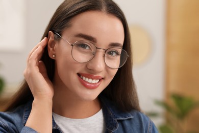 Photo of Portrait of beautiful young woman with glasses indoors. Attractive lady smiling and looking into camera