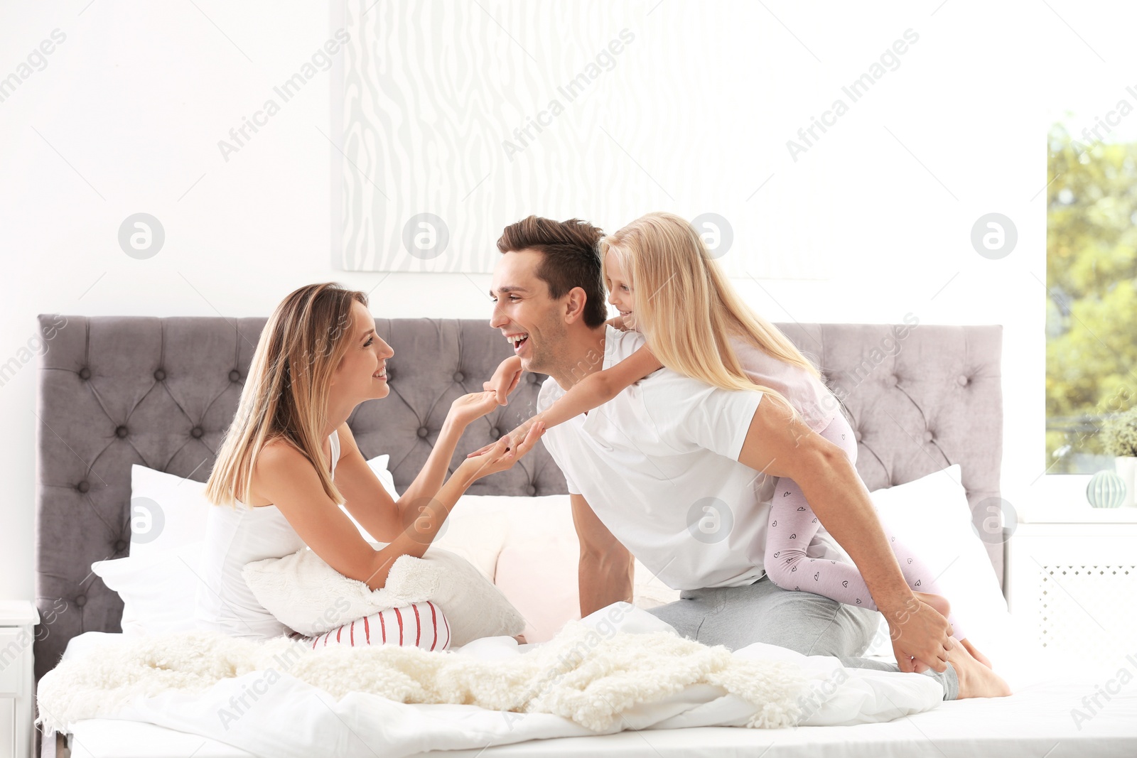 Photo of Happy family having fun on bed with pillows at home. Weekend morning