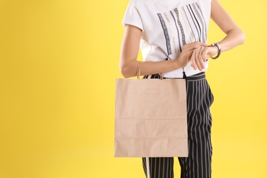 Young woman with shopping bag on color background. Mockup for design