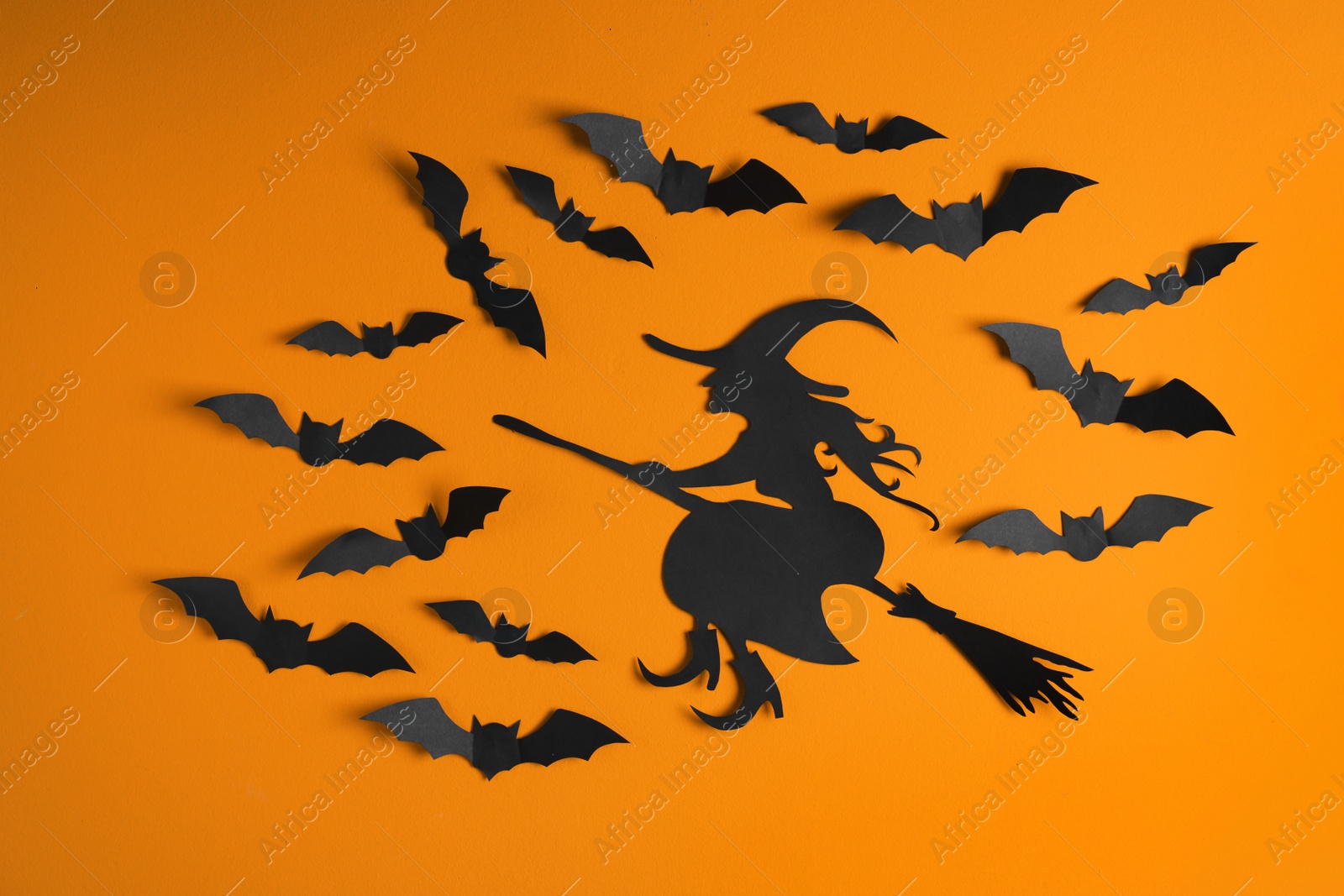 Photo of Paper bats and witch cutout on color background. Halloween decor