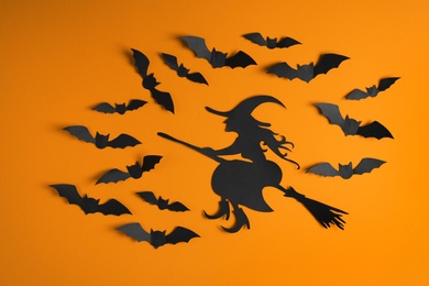 Paper bats and witch cutout on color background. Halloween decor