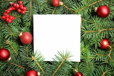 Photo of Blank paper sheet with Christmas decoration on fir tree branches as background