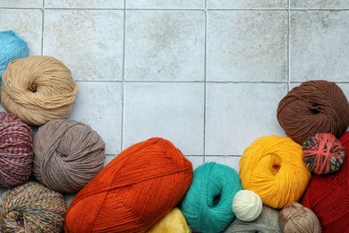 Photo of Soft woolen yarns on grey tiled background, flat lay. Space for text