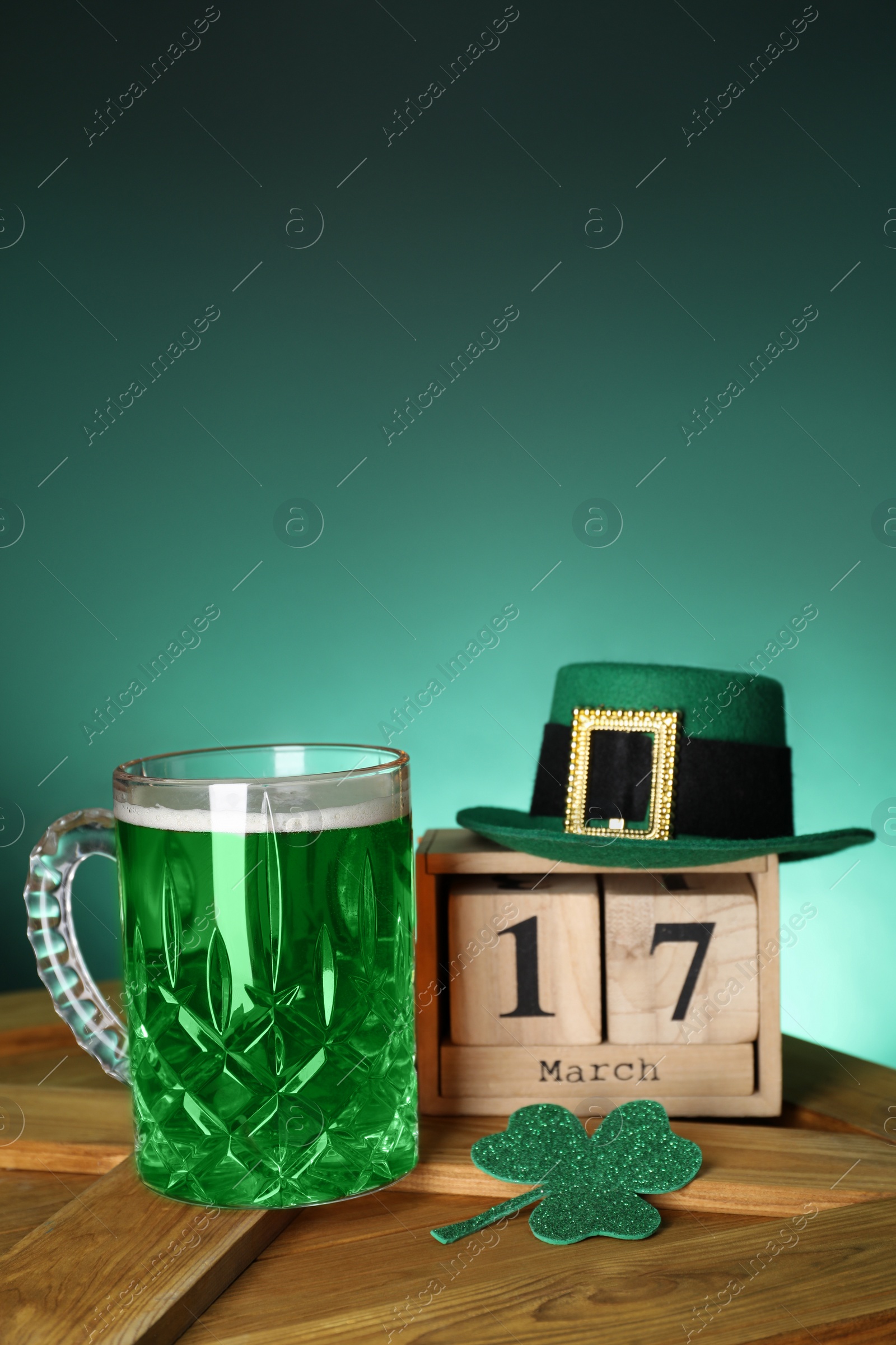 Photo of St. Patrick's day celebrating on March 17. Green beer, block calendar, leprechaun hat and decorative clover leaf on wooden table