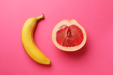 Photo of Banana and half of grapefruit on pink background, flat lay. Sex concept
