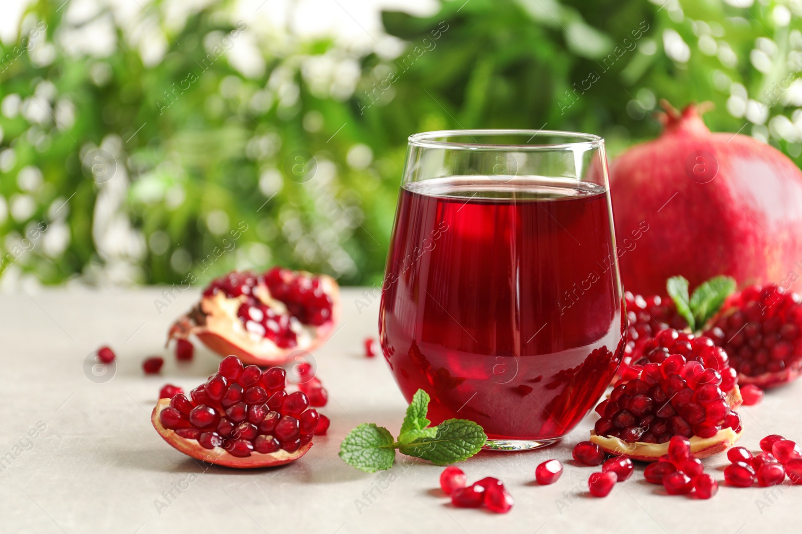 Photo of Composition with glass of fresh pomegranate juice on table. Space for text