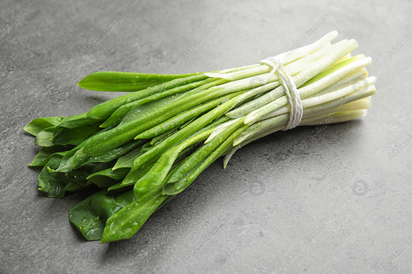 Photo of Bunch of wild garlic or ramson on grey table, closeup