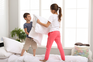 Happy children having pillow fight in bedroom