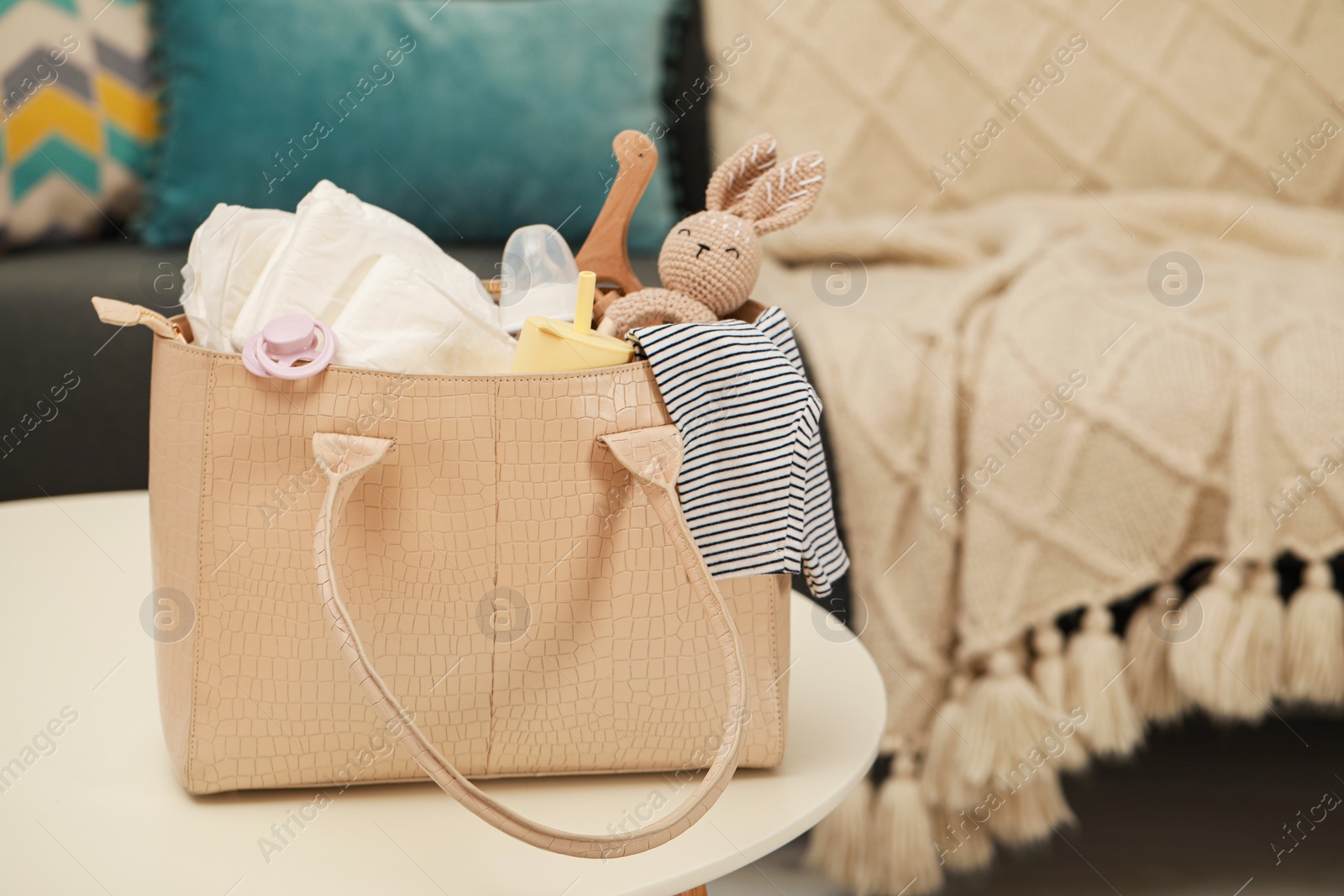 Photo of Mother's bag with baby's stuff on white table indoors. Space for text