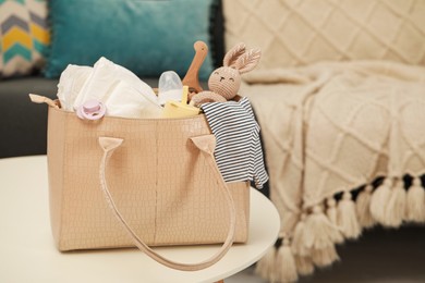 Photo of Mother's bag with baby's stuff on white table indoors. Space for text