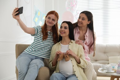 Photo of Happy pregnant woman taking selfie with friends at baby shower party