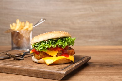 Photo of Delicious tofu burger served with french fries on wooden table, space for text