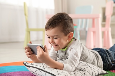 Photo of Little boy using video chat on smartphone in playroom