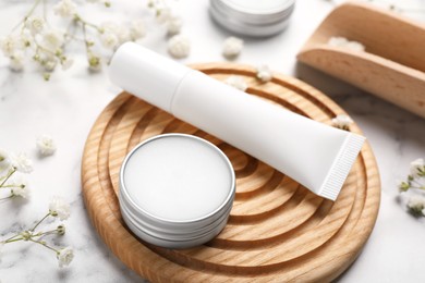 Photo of Lip balms and gypsophila flowers on white marble table