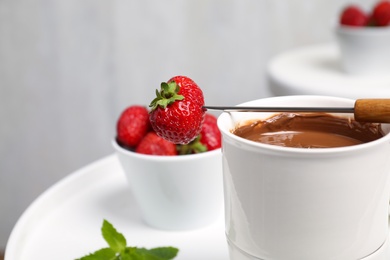 Photo of Fondue pot with chocolate and strawberry on white table