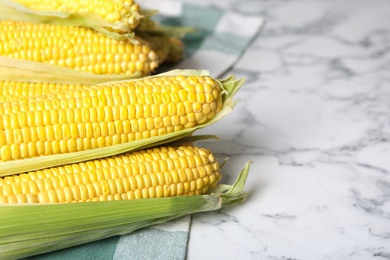 Photo of Bunch of corn cobs on white marble table, closeup