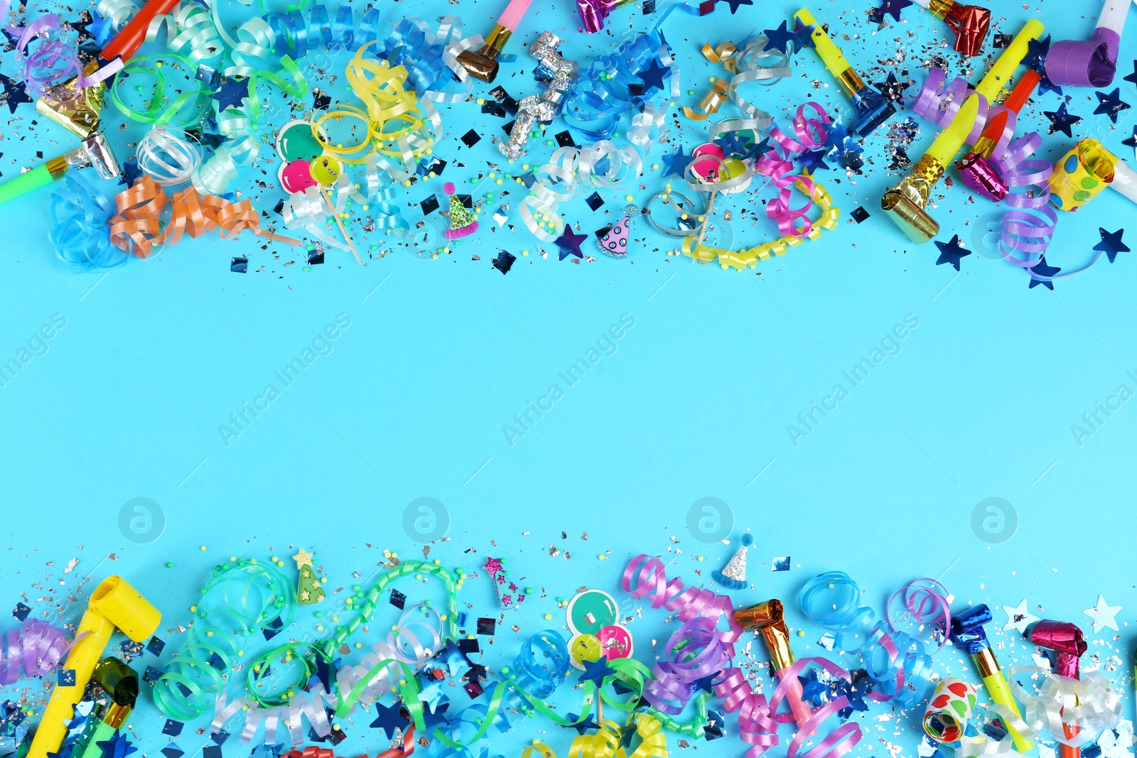 Photo of Colorful serpentine streamers, confetti and party horns on light blue background, flat lay. Space for text