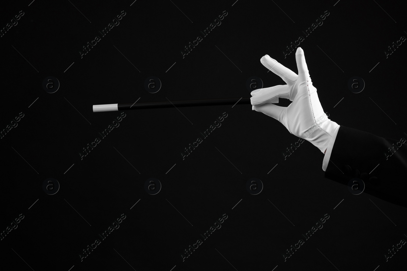 Photo of Magician holding wand on black background, closeup