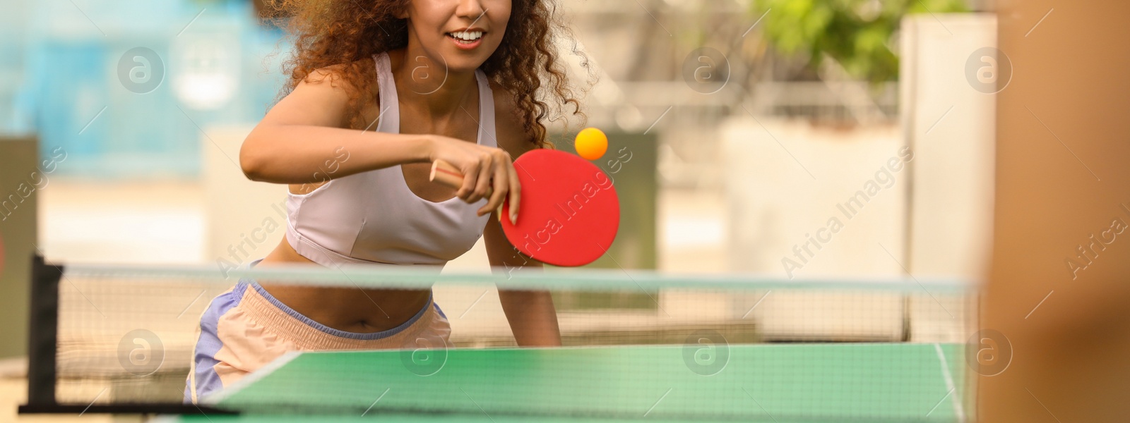 Image of African-American woman playing ping pong with friend outdoors. Banner design