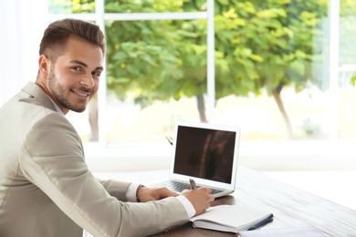 Man in office wear using laptop at table indoors