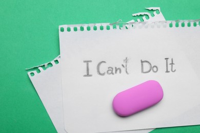 Photo of Motivation concept. Paper with changed phrase from I Can't Do It into I Can Do It by erasing letter T on green background, top view