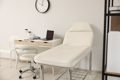 Photo of Modern medical office with doctor's workplace and examination table in clinic